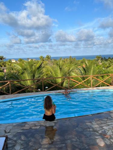 a woman sitting in a pool looking out at the ocean at Pipa Golfinhos Pousada in Pipa
