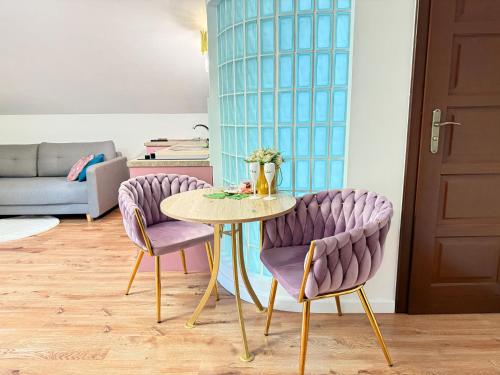 a table and two purple chairs in a living room at Apartament Premium Cichowo in Cichowo