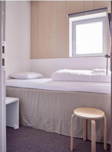 une chambre avec un lit avec un tabouret et une fenêtre dans l'établissement Dayroom Espace Paris sans nuitée et Chambre partagée Chatillon nuitée -- Repos journée ou Espace Travail 8-19h Proche Tour Eiffel ou Usage bureau à l'heure en journée -- Nuitée Chatillon Avenue Paris, à Paris