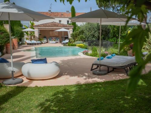 une cour avec une piscine bordée de parasols dans l'établissement La Sarrazine, à Les Mées