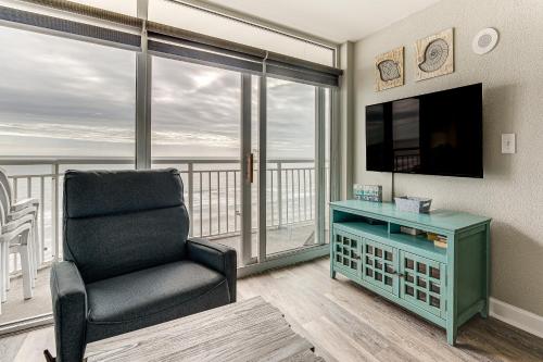 a living room with a chair and a television at Oceanfront North Myrtle Beach Gem Pools Access! in Myrtle Beach