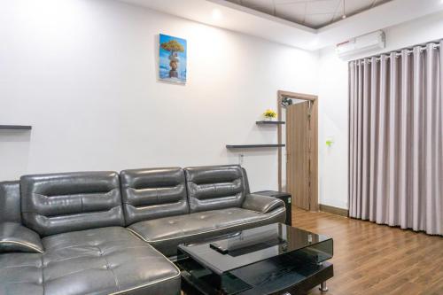 a living room with a leather couch and a table at Cherry homestay bmt phòng đôi gia đình in Buôn Ðũng
