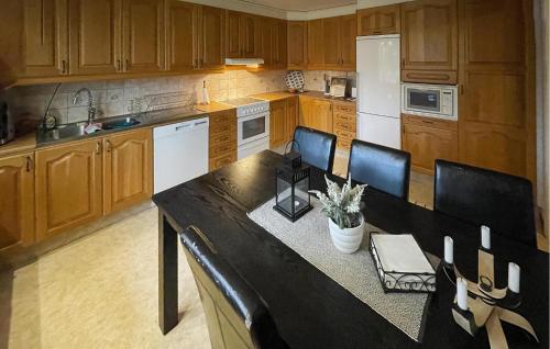 a kitchen with wooden cabinets and a black table and chairs at 3 Bedroom Gorgeous Home In Ljungby in Ljungby