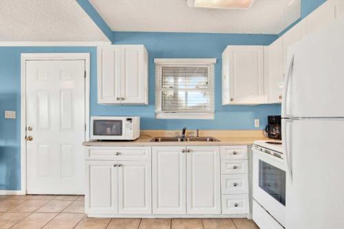 a kitchen with white cabinets and a white refrigerator at Ocean front Rental 101-2 in Tybee Island