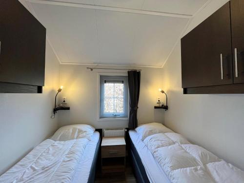 two beds in a small room with a window at Lakeside Farm Stay, Friesland in Sint Nicolaasga