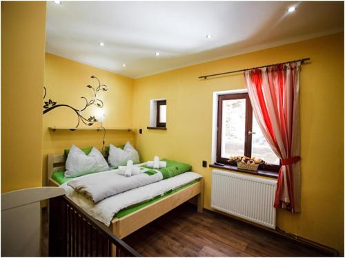a bed in a room with yellow walls and a window at Villa in Staré Hamry near Ski Park Grun in Staré Hamry