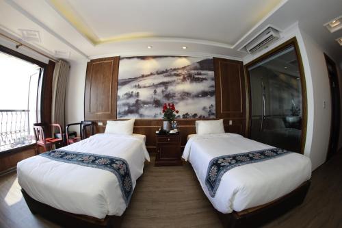 two beds in a room with a painting on the wall at Delta Sapa Hotel - Old Quarter Center in Sa Pa