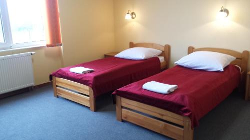 two beds in a room with red sheets at Noclegi Apro in Gdańsk
