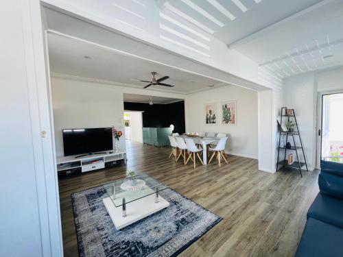 Una sala de estar con televisión y un comedor. en House at the Heart of Entrance! Sleeps20, en The Entrance