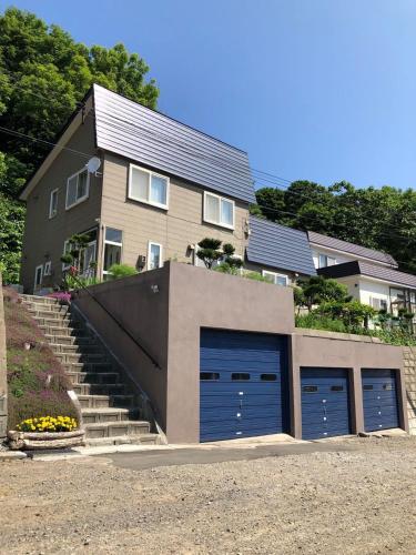 a house with two blue garage doors and stairs at 小樽祝津山荘2号楼 in Otaru