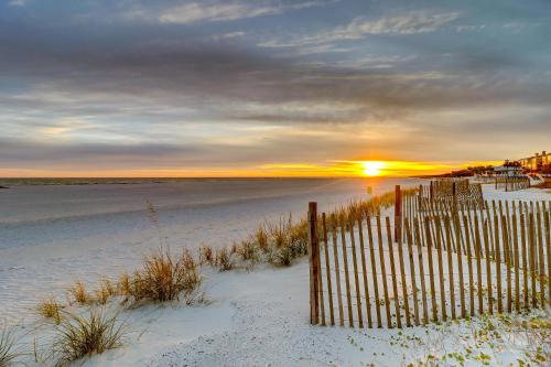 a fence on the beach with the sunset in the background at SG8C: 8C Seagrove Villa in Isle of Palms