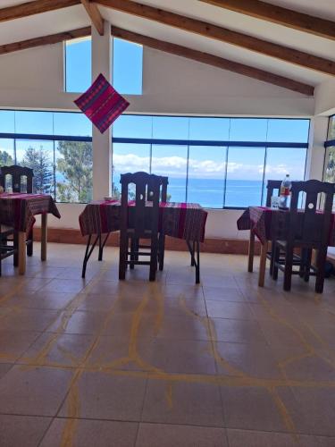 a dining room with tables and chairs and windows at Palacio del Inca Lodge in Comunidad Yumani