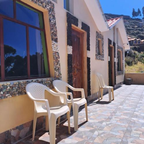 two white chairs sitting on the side of a building at Palacio del Inca Lodge in Comunidad Yumani