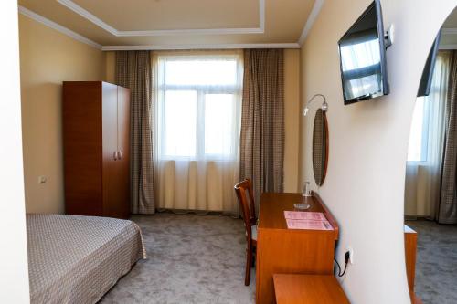 a hotel room with a bed and a desk and a television at Hotel Bulgaria in Kŭrdzhali