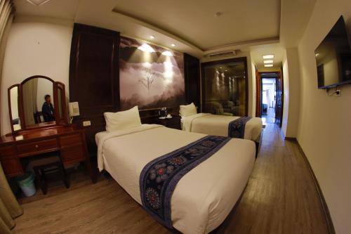 a hotel room with two beds and a mirror at Delta Sapa Hotel - Old Quarter Center in Sa Pa