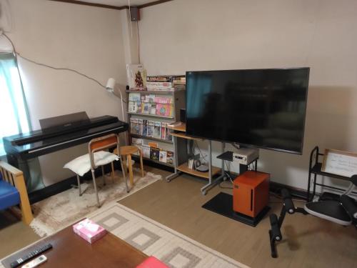 a living room with a flat screen tv and a piano at Private Retreat Nagasaki Vogelnest 2階貸切長崎スタジアムシティ入口5分 in Nagasaki