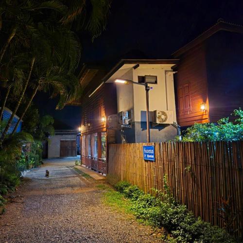 a house on a street at night with a fence at Kedthawa Homestay เฮือนเก็ดถะหวา in Ban Cho Lae