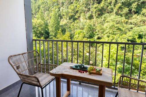 a table and chairs on a balcony with a view at 凤凰苇渡庭院江景民宿 in Fenghuang