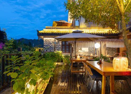 a patio with a table and an umbrella at 凤凰苇渡庭院江景民宿 in Fenghuang