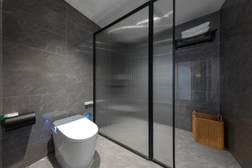 a bathroom with a toilet and a glass shower at 凤凰苇渡庭院江景民宿 in Fenghuang