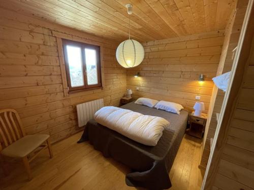 une chambre avec un lit dans une cabane en bois dans l'établissement Chalet spacieux avec balcon et cuisine équipée - FR-1-787-112, à Laveissière