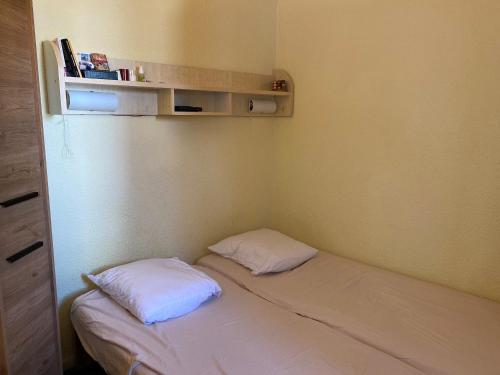 Cette petite chambre comprend un lit avec deux oreillers. dans l'établissement Appart. skis aux pieds, sud, animaux bienvenus - FR-1-513-99, à Courchevel
