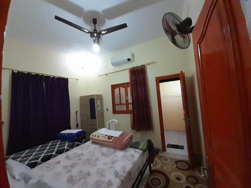 a bedroom with a bed and a ceiling fan at Tata Guest House in Tatta