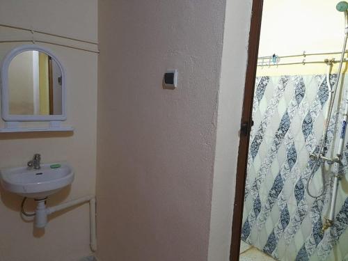 a bathroom with a sink and a shower curtain at Tata Guest House in Tatta