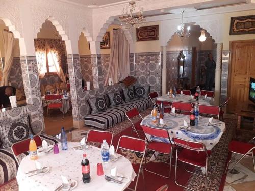 a restaurant with tables and chairs and a couch at Tata Guest House in Tatta
