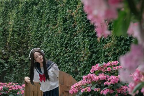 a girl with a red bow in her hair standing next to flowers at Lijiang Hearing Flower Hall Garden Inn Butterfly Language Shop in Lijiang