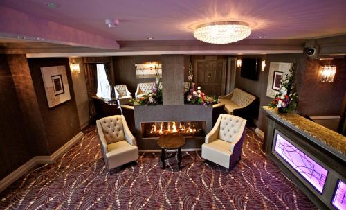 a lobby with a fireplace and chairs and a table at Greenvale Hotel in Cookstown
