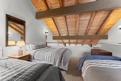 two beds in a room with wooden ceilings at Lake Escape in Carnelian Bay