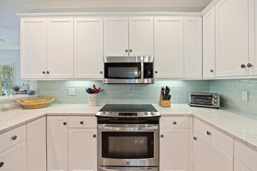a kitchen with white cabinets and a stove top oven at OG23: 23 Ocean Green in Kiawah Island