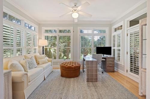 a living room with a couch and a tv and windows at OG23: 23 Ocean Green in Kiawah Island