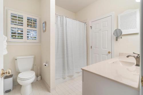 a white bathroom with a toilet and a sink at OG23: 23 Ocean Green in Kiawah Island