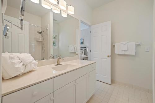 a white bathroom with a sink and a mirror at OG23: 23 Ocean Green in Kiawah Island