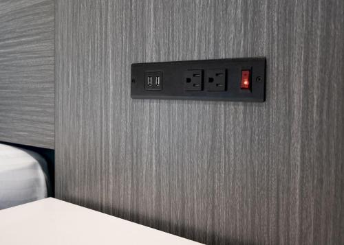 a lightswitch on a wall next to a bed at La Mirage Inn - Long Beach in Long Beach
