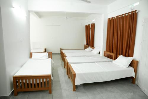 a row of four beds in a room at Jayalakshmi Residency in Vaduvanchal