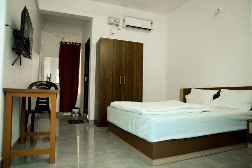 a bedroom with a bed and a wooden cabinet at Jayalakshmi Residency in Vaduvanchal