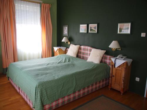 Dormitorio verde con cama y ventana en Gasthof Gerlinde Gibiser en Heiligenkreuz im Lafnitztal
