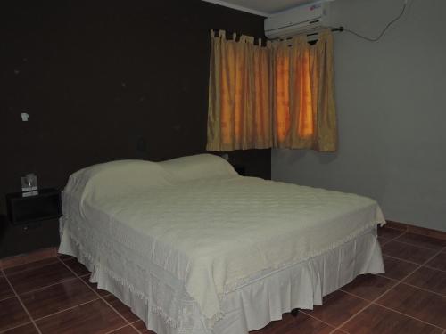 Bett in einem Zimmer mit einem Fenster und einer weißen Tagesdecke in der Unterkunft Apartamento Brisas del Golf in Colón