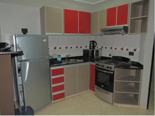 cocina con armarios rojos y amarillos y nevera en Apartamento Brisas del Golf en Colón