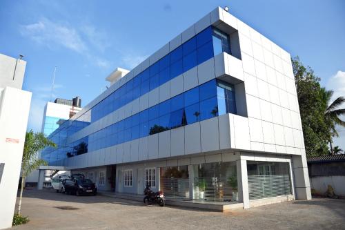 a large glass building with a motorcycle parked in front at Jayalakshmi Residency in Vaduvanchal
