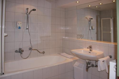 ein Bad mit einer Badewanne, einem Waschbecken und einer Dusche in der Unterkunft Gasthof Gerlinde Gibiser in Heiligenkreuz im Lafnitztal