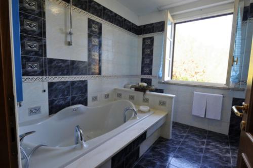 a bathroom with a tub and a sink and a window at Holiday House Aurora in Cortona