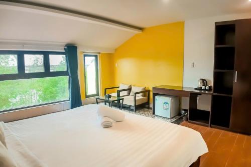 a bedroom with a large white bed and a desk at The Cuckoo's Nest Hostel and Bar managed by Hoianese in Hoi An