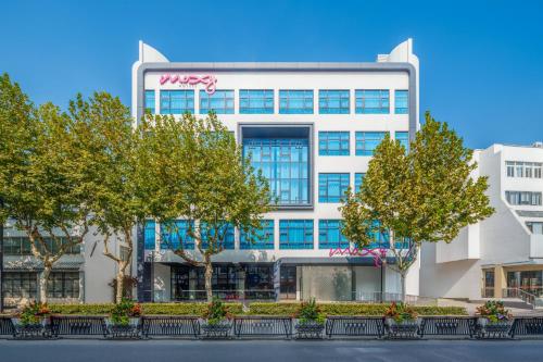 an office building with trees in front of it at Moxy Suzhou City Centre in Suzhou