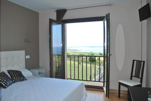 a bedroom with a bed and a balcony with a view at El Ribero de Langre in Langre