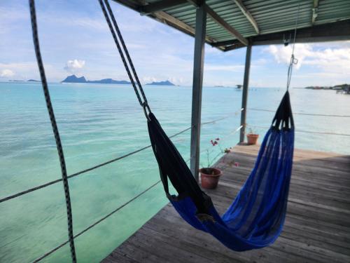a blue hammock hanging on a dock next to the ocean at Bigfin water bungalow in Semporna