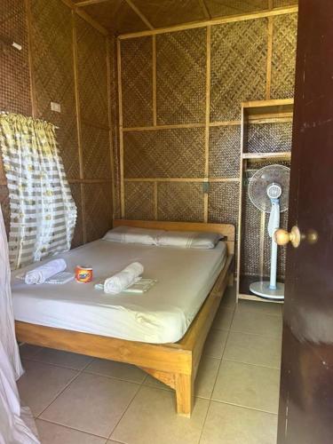 a small bed in a room with a fan at Diamond De Siquijor Beach House in Siquijor